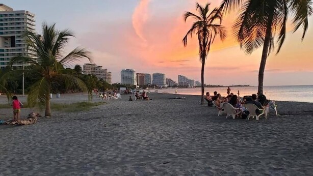 Una playa con palmeras y un atardecer.
