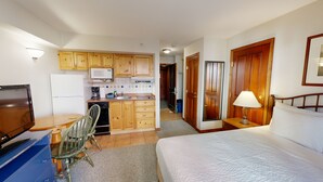 Une chambre d’hôtel de taille réduite comprenant un lit, un bureau avec une télévision, une kitchenette et une salle de bain.