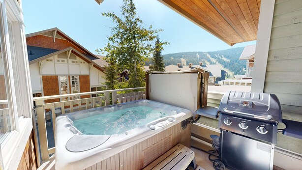 A balcony with a hot tub, a grill, and a view of a mountainous landscape. - Settler's Crossing #42 (Sun Peaks)