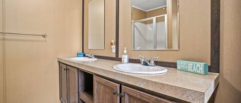 A bathroom with two sinks, wooden cabinets, a towel rack, and a mirror.