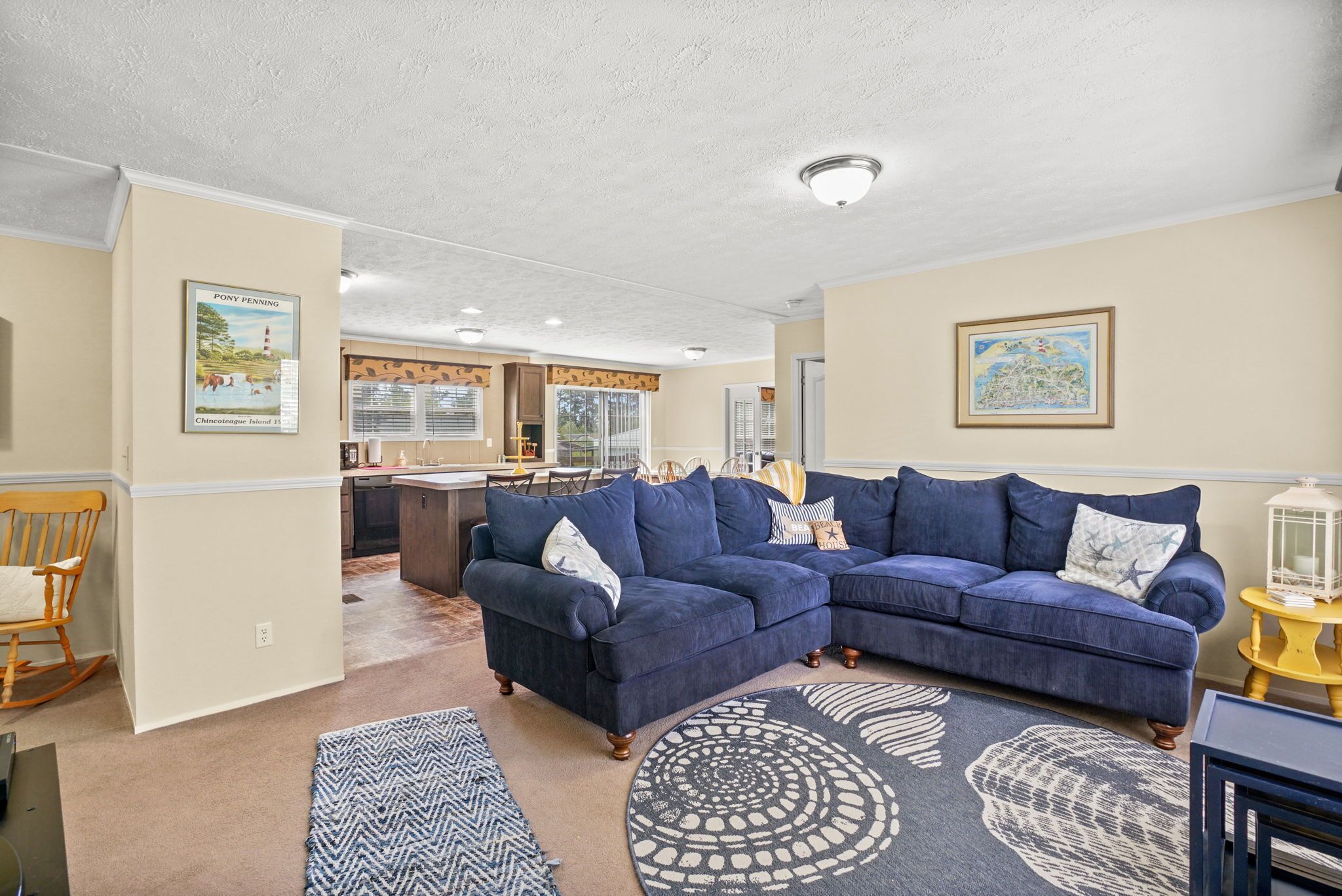 A living room with a blue sectional sofa, a wooden rocking chair, and a patterned rug.