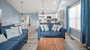 A modern living room with a blue sofa set, a wooden coffee table, and a ceiling fan.