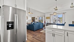 Una cuina moderna amb armaris blancs, un refrigerador d'acer inoxidable i un sòl de fusta.