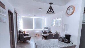 Uma cozinha moderna com bancada de mármore, banquetas, cafeteira e relógio de parede.