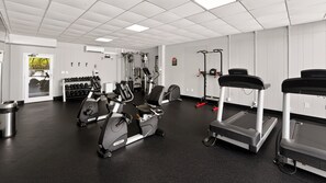 Une salle de sport équipée de divers appareils d’exercice, notamment des tapis de course, des vélos d’appartement et des appareils de musculation.