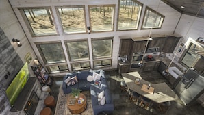 A spacious living area with a large sectional sofa, a coffee table, and a fireplace. There are multiple windows providing natural light and views of the outdoors. - Star-Spangled Fun | Arcade + Outdoor Oasis + Putt-Putt + EV Outlet (Broken Bow)