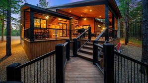 Une cabane en bois dotée d’une terrasse et d’un escalier menant à l’entrée.