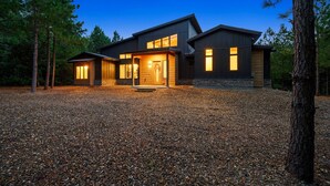 Une maison moderne avec une allée en gravier, entourée d’arbres.