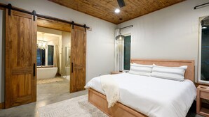 Une chambre à coucher avec un lit en bois, une grande porte coulissante, un lustre et une vue sur la salle de bain.