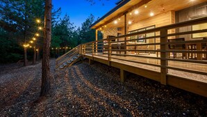 Une terrasse en bois dotée d  ’une rambarde, qui mène à un bâtiment avec de grandes fenêtres et un mur en briques.