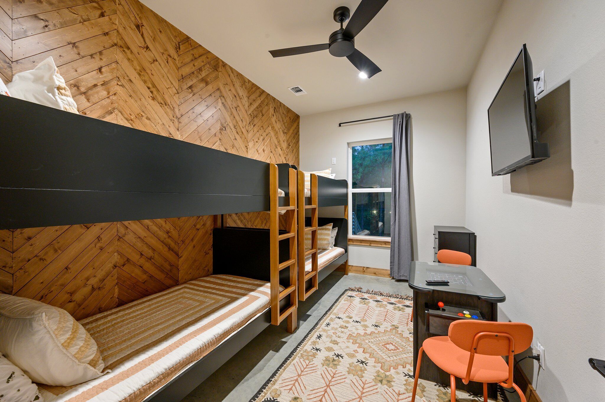 A compact room with bunk beds, a desk, a chair, and a TV.