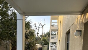 Un balcón con baranda blanca que da a un jardín con césped y un edificio con varias ventanas y balcones.
