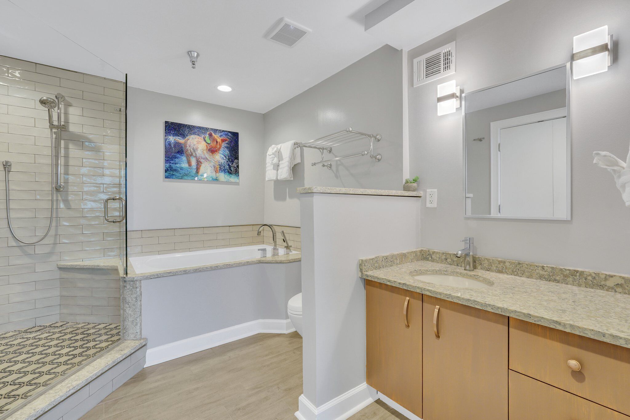 A modern bathroom with a glass-enclosed shower, a freestanding bathtub, a granite countertop sink, wooden cabinets, and a large mirror.