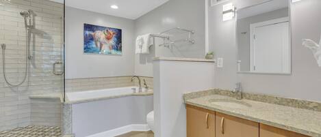 A modern bathroom with a glass-enclosed shower, a freestanding bathtub, a granite countertop sink, wooden cabinets, and a large mirror.