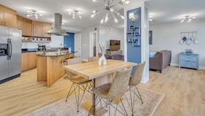 Una cucina moderna con mobili in legno, un'isola centrale e un'area pranzo con tavolo e sedie in legno.