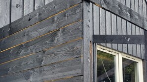 A wooden building with a window and a light fixture. - The Quarterdeck (Portree)