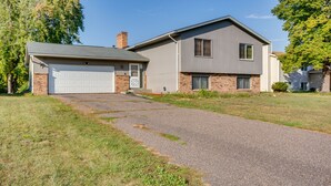 Ein zweistöckiges Haus mit Garage, Backsteinfundament und Auffahrt zur Haustür.