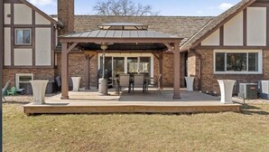 Un patio couvert avec une table et des chaises, une poubelle et, au fond, un bâtiment en briques.
