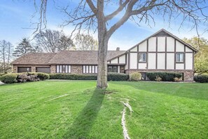 A two-story house with a large lawn, a tree in the front yard, and a clear sky. - Your playoff headquarters near Notre Dame. (Granger)