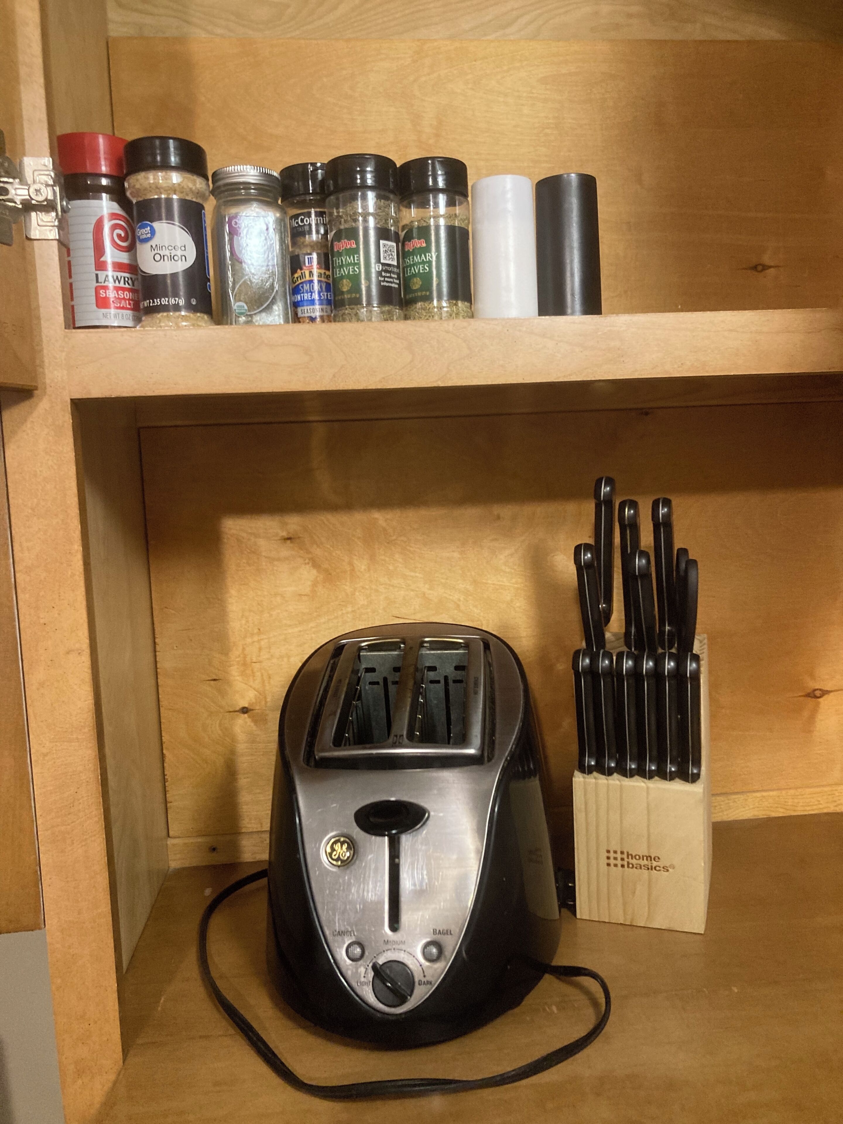 A kitchen with a toaster and a spice rack on a wooden shelf.