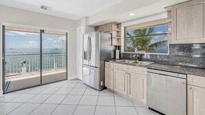 Una cocina moderna con vista al océano, un refrigerador y un lavamanos.