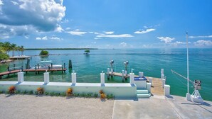 Un puerto deportivo con barcos amarrados, un cielo azul despejado y una isla a lo lejos.