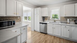 Una cocina moderna con armarios blancos, un microondas integrado y un lavavajillas.