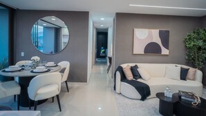 A modern living room with a round dining table, a sofa, and a large mirror. - Apartment Luxe with view of Poblado (Envigado)