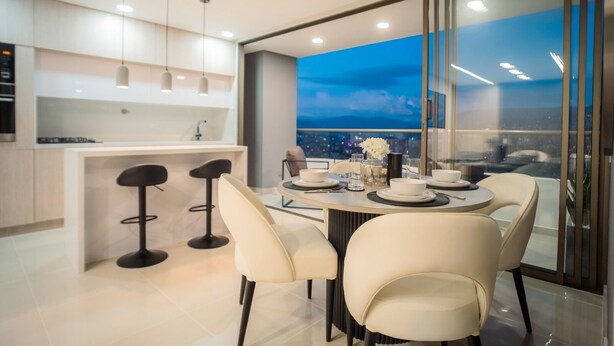 A modern kitchen with a dining area, featuring a large window with a city view at night. - Apartment Luxe with view of Poblado (Envigado)
