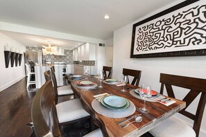 A dining area with a long wooden table set for four, surrounded by chairs. - City View Sanctuary ~ Hot Tub, Abundant Parking, 3 Decks, Fenced Yard, Fire Pit (Pittsburgh)