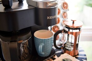 A Keurig coffee maker, a blue mug, and a copper coffee pot on a table. - City View Sanctuary ~ Hot Tub, Abundant Parking, 3 Decks, Fenced Yard, Fire Pit (Pittsburgh)
