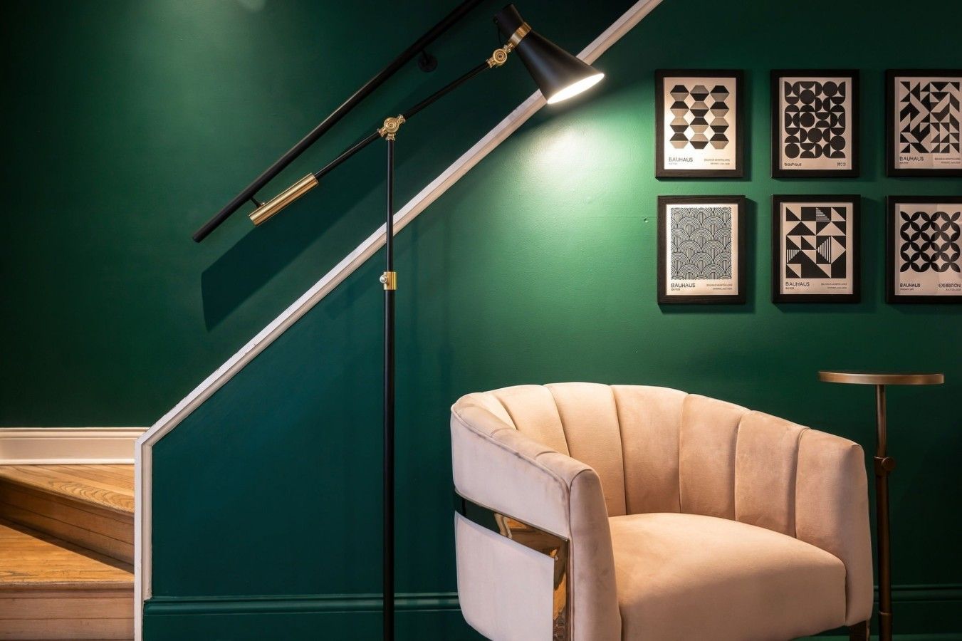 A staircase with a modern design, a beige armchair, and a wall with framed geometric patterns.