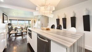 A modern kitchen with a marble countertop, a built-in oven, and a dining area with a view. - City View Sanctuary ~ Hot Tub, Abundant Parking, 3 Decks, Fenced Yard, Fire Pit (Pittsburgh)