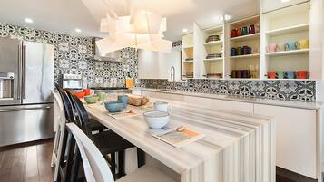 A modern kitchen with a central island, white cabinetry, and a patterned backsplash.
