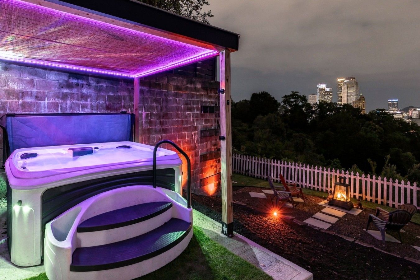 A spa area with a hot tub and a wooden deck overlooking a cityscape.