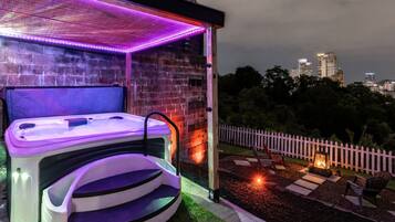 A spa area with a hot tub and a wooden deck overlooking a cityscape.
