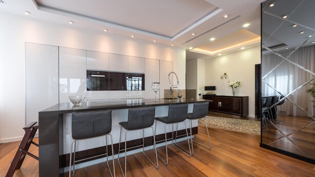 Une cuisine moderne dotée d’un îlot central, de tabourets de bar et d’un coin repas comprenant un canapé et des chaises.