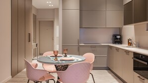 Une cuisine moderne avec une table de salle à manger ronde, des chaises roses et une machine à café.