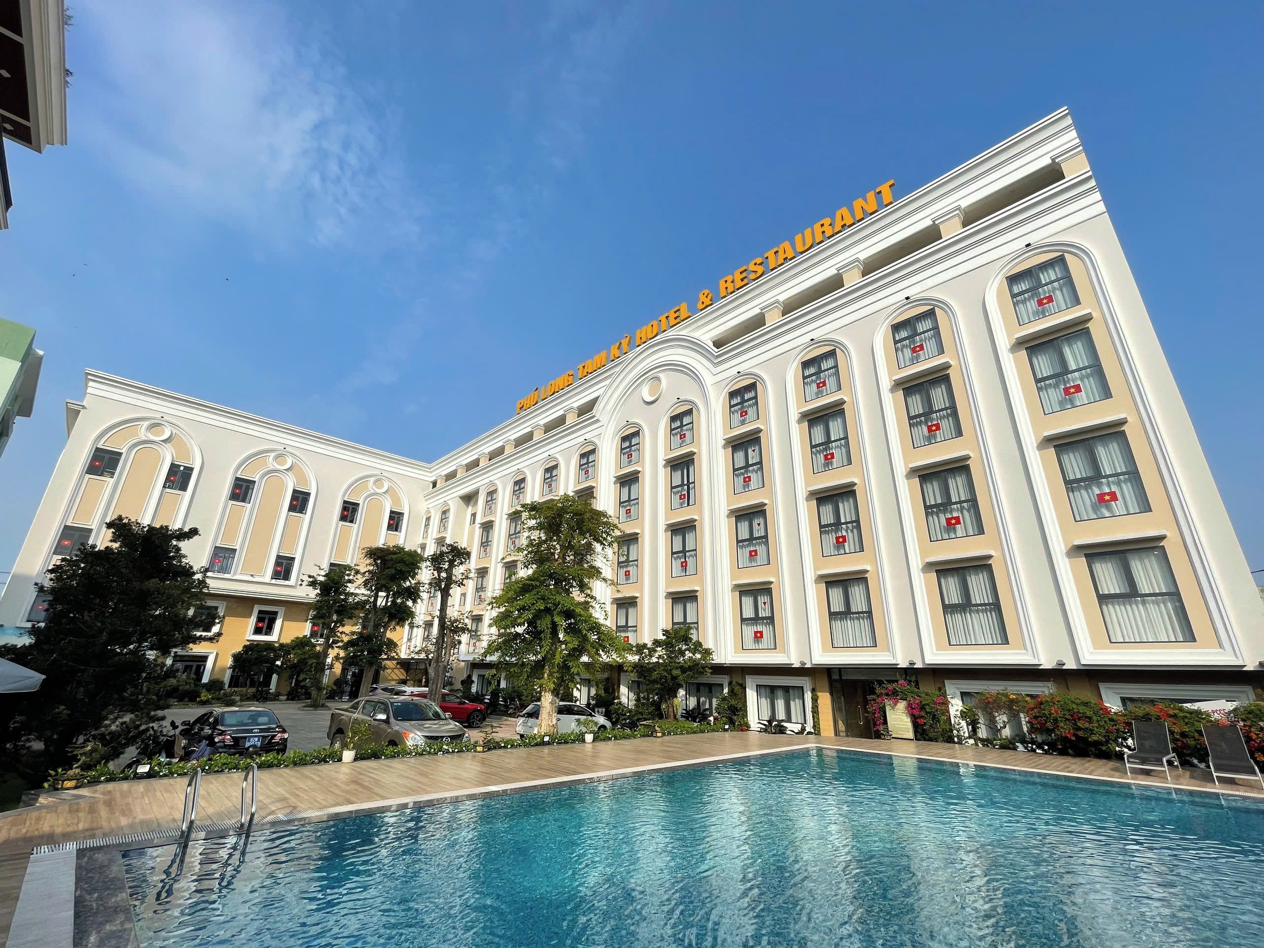 Un hotel con piscina, varios balcones y un cielo despejado.