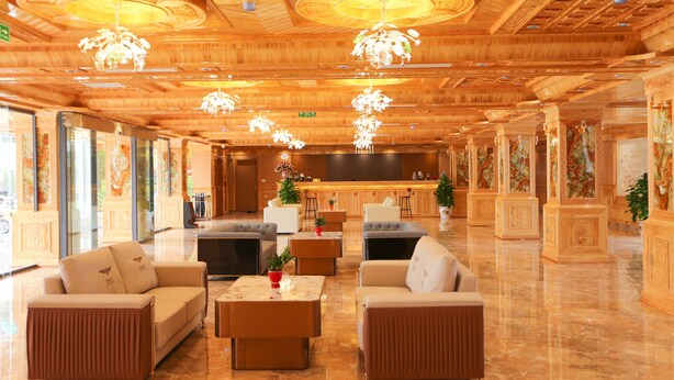 Un hall espacioso con techo de madera, varias zonas de estar y un bar central.
