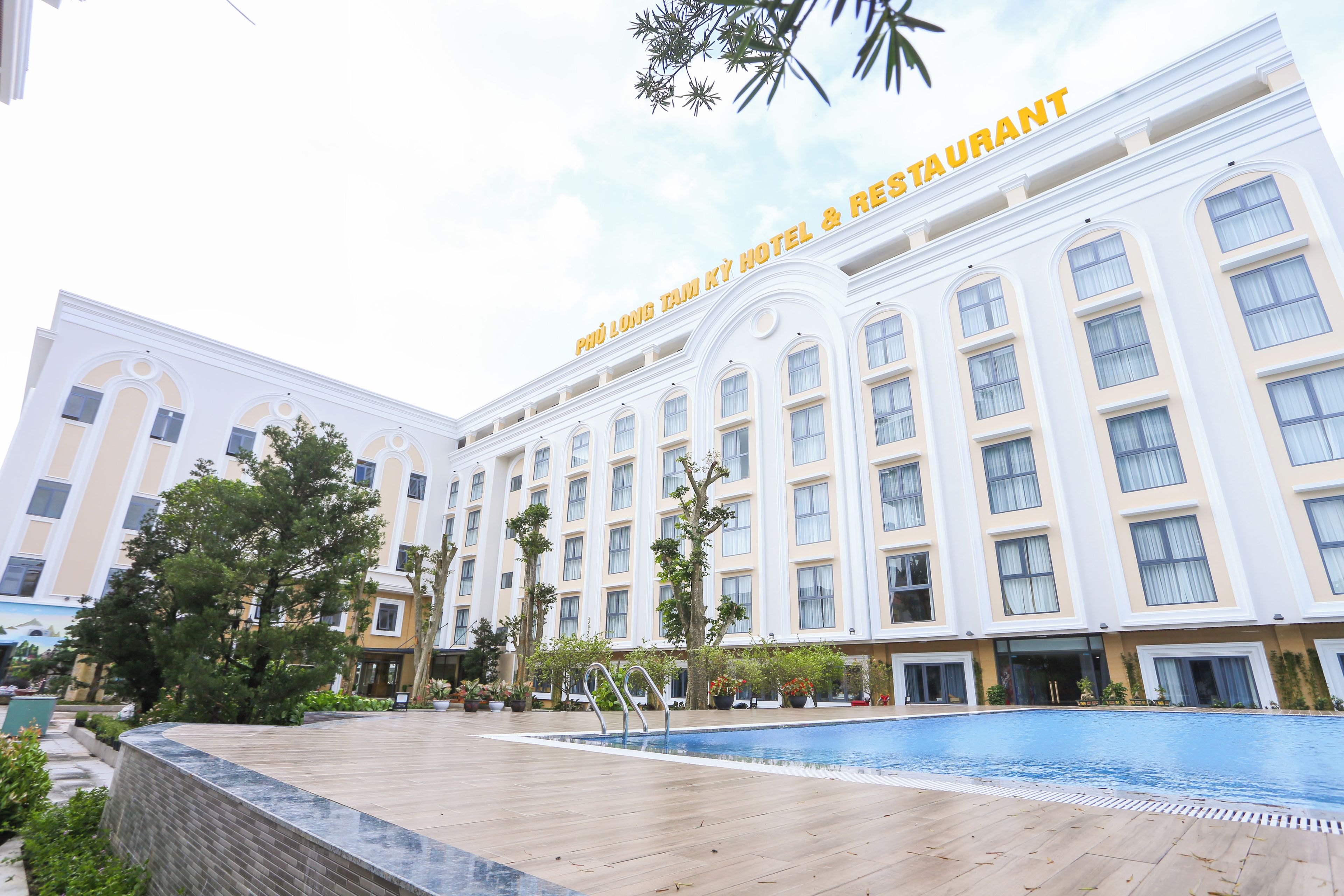 A hotel with a swimming pool, multiple floors, and a sign indicating a restaurant.