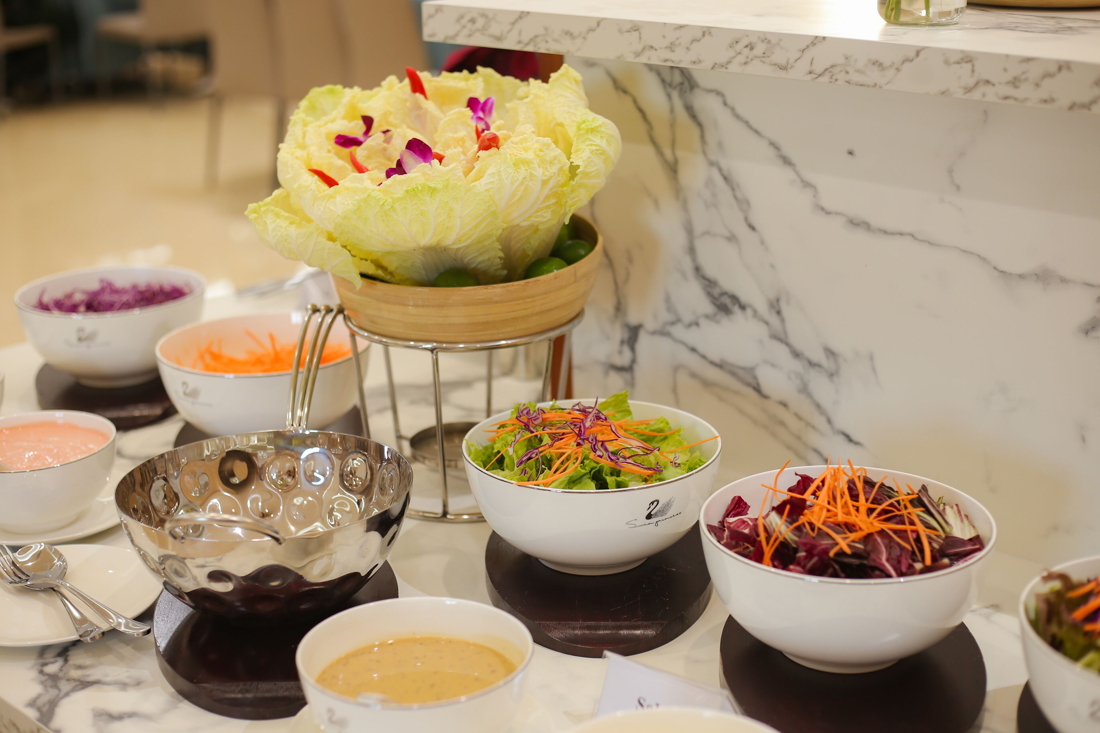 A variety of food bowls on a marble countertop, including salads and dips.