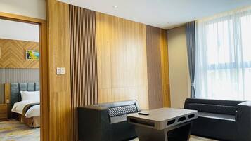A modern hotel room with a bed, a sofa, a coffee table, and a large window with curtains.