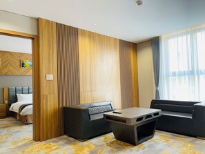 A modern hotel room with a bed, a sofa, a coffee table, and a large window with curtains. - Phu Long Tam Ky Hotel & Restaurant (Da Nang)