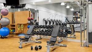 A gym with exercise equipment, a mirror, and a television.