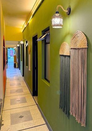 Un couloir avec un mur vert, un luminaire suspendu et un motif décoratif sur le mur.