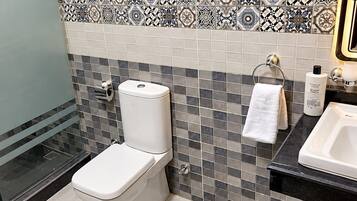 Un baño con inodoro, lavamanos y un salpicadero de azulejos estampados.