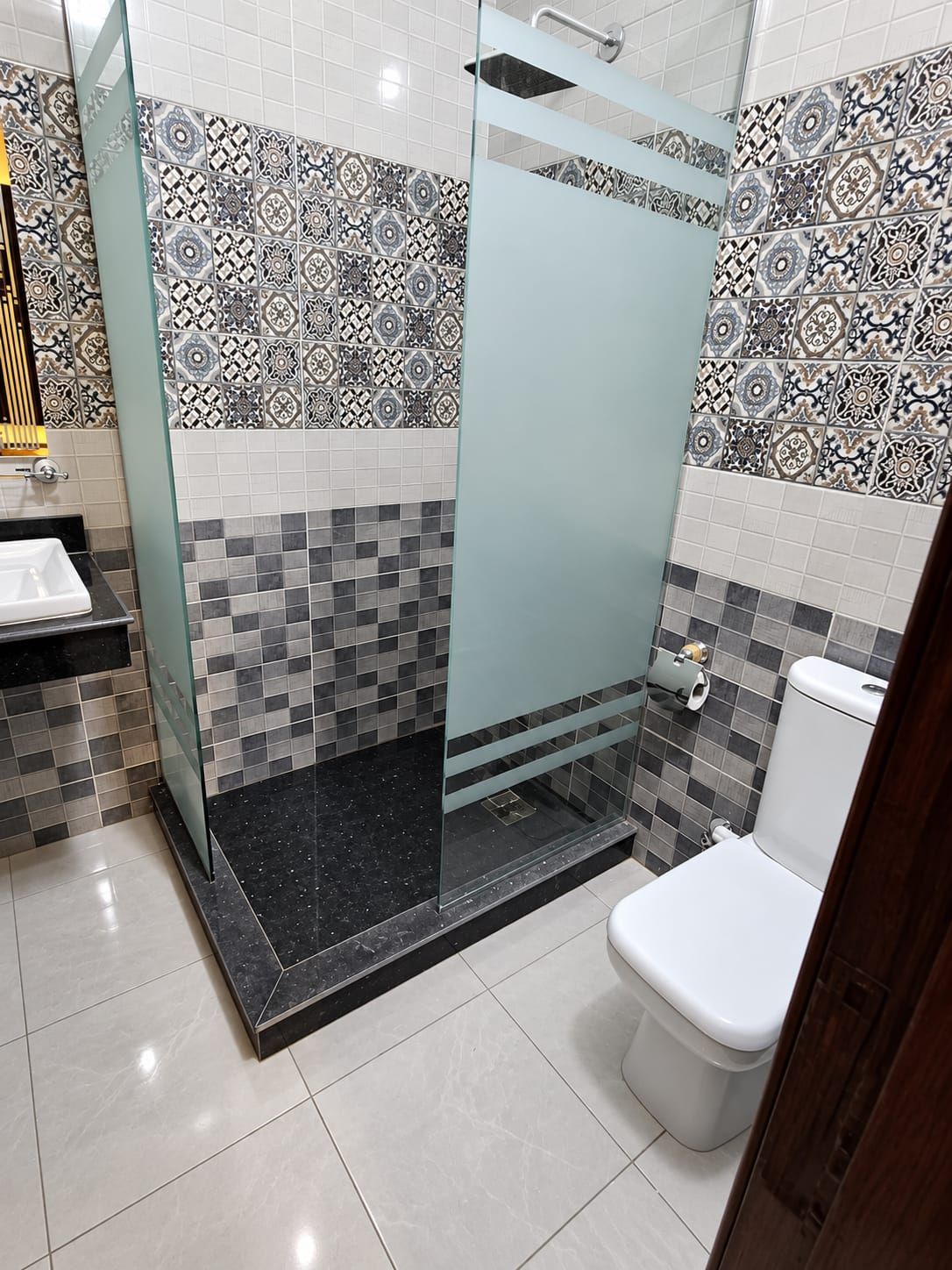 Un baño con cabina de ducha de vidrio, inodoro y lavamanos.