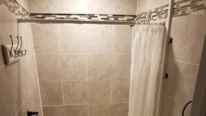 A small, tiled bathroom with a shower, a sink, and a toilet. - Comfortable cabin in the mountains of North Carolina, located near TIEC. (Mill Spring)