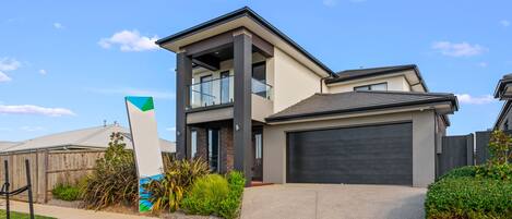 A modern two-story house with a garage, a balcony, and a well-maintained lawn.
